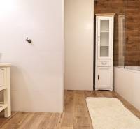 Badezimmer mit weißen Fliesen und Boden in Holzoptik in einer 3-Zimmer-Wohnung.