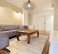 Wohnzimmer in einer 3-Zimmer-Wohnung mit Sofa, Holztisch und Boden mit Holzdekor.