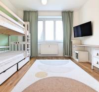 Ein Zimmer in einer 3-Zimmer-Wohnung mit einem Etagenbett, einem Fernseher und einem Boden in Holzoptik.