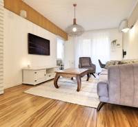 Wohnzimmer mit Sofa und Sessel in einer 3-Zimmer-Wohnung mit Holzboden.