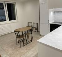 Küche in einer Einzimmerwohnung mit Esstisch, Schränken und dekorativen Bildern an der Wand.