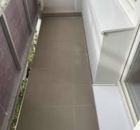 Ein schmaler Balkon mit Keramikfliesen in einer Einzimmerwohnung.