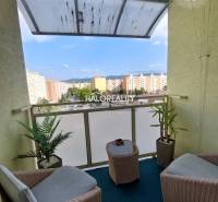 Balkon einer 3-Zimmer-Wohnung mit Rattanmöbeln und Blick auf die Siedlung in Prievidza.