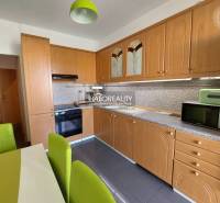 Küche in einer 3-Zimmer-Wohnung mit Holzküche und grünen Stühlen.