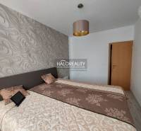 Schlafzimmer in einer 3-Zimmer-Wohnung mit gemusterten Tapeten und Betten mit Decken.