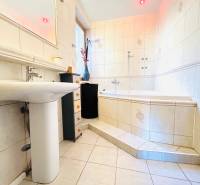 Badezimmer mit Badewanne, Waschbecken und Fliesen in einer 2-Zimmer-Wohnung.