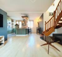 Wohnzimmer in einer 2-Zimmer-Wohnung mit Küche und Treppe, Boden mit Holzdekor.