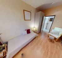 Ein Zimmer mit Bett, Stuhl und Holzboden in einer 3-Zimmer-Wohnung.