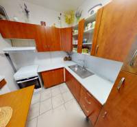 Küche in einer 3-Zimmer-Wohnung, mit Holzdekor, Schränke und weiße Arbeitsplatte.