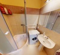 Badezimmer in einer 3-Zimmer-Wohnung mit Badewanne, Waschmaschine und Waschbecken, helle Fliesen.