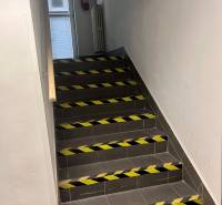 Treppe mit Stützgeländer, markiert mit Warnbändern in Geschäftsräumen.