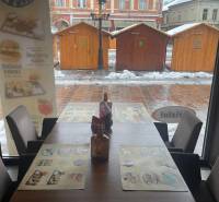 Winterlandschaft durch das Fenster eines Gastronomiebereichs mit Blick auf Holztische.