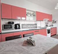 Küche in einem Einfamilienhaus mit rosa Schränken und einem weißen Tisch.