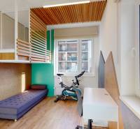 Kinderzimmer mit Bett, Schreibtisch, Teppich, Holzboden und Fahrrad.