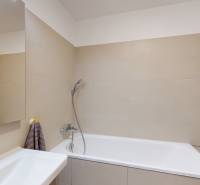 Badezimmer mit Badewanne und beigen Fliesen in einer Vierzimmerwohnung.