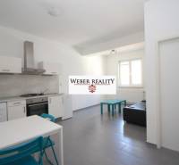 Wohnzimmer in einer 2-Zimmer-Wohnung mit Küchenzeile, einfacher Einrichtung und Fenster.