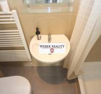 Badezimmer in einer 2-Zimmer-Wohnung mit Duschkabine und Keramikwaschbecken.