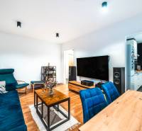 Wohnzimmer einer Zweizimmerwohnung mit Holzboden und blauen Sofas.