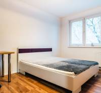 Schlafzimmer mit Bett, Tisch und Boden in Holzdekor in einer 2-Zimmer-Wohnung.
