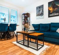 Wohnzimmer in einer 2-Zimmer-Wohnung mit einem blauen Sofa und einem Boden in Holzoptik.