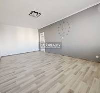 Ein Zimmer mit einer Uhr und einem Boden in Holzoptik in einer 2-Zimmer-Wohnung.