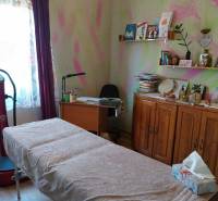 Ein Zimmer in einem Einfamilienhaus mit einem Massagetisch, einem Schreibtisch und Bücherregalen.