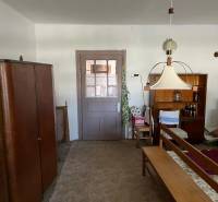 Innenraum eines Einfamilienhauses mit Möbeln und Teppich, zentrale Lampe und Regal mit Getränken.