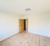 Zimmer in einer 3-Zimmer-Wohnung mit weißen Wänden und einem Boden in Holzoptik.