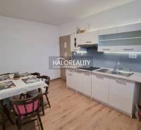 Ein Einfamilienhaus in Poprad mit Rasen, Holzzaun und Nadelbäumen im Hintergrund.