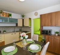 Küche in einer Einzimmerwohnung mit Esstisch und Boden in Holzoptik.