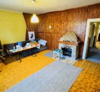 Wohnzimmer in einem Einfamilienhaus mit Kamin und Holzverkleidung an den Wänden.