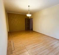 Wohnzimmer mit Holzboden, Kronleuchter und gemusterter Wand in einer 3-Zimmer-Wohnung.