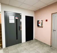 Ein Flur mit Treppen, Aufzug, Fliesen und Feuerlöscher in einer 3-Zimmer-Wohnung.