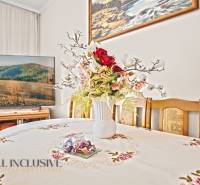 Esszimmer in einem Einfamilienhaus mit Blumendekoration auf dem Tisch und einem Fernseher im Hintergrund.