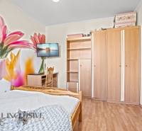 Ein Schlafzimmer in einem Einfamilienhaus mit einer Blumentapete, einem Holzboden und Möbeln.