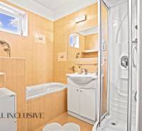 Ein Badezimmer in einem Einfamilienhaus mit einer Badewanne, einer Dusche und einem Spiegel auf ockerfarbenen Fliesen.