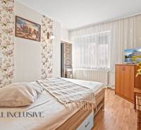 Schlafzimmer im Einfamilienhaus mit Bett, Tapete mit Blumen und Boden mit Holzdekor.