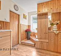 Ein Flur in einem Einfamilienhaus mit Holzverkleidung, Dekorationen und einem Boden mit Holzdekor.