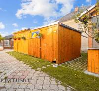 Der Hof des Einfamilienhauses in Dunajská Streda mit einem Holzunterstand und einem gepflasterten Weg.