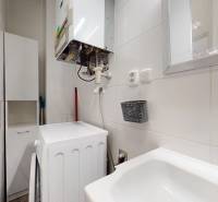 Badezimmer einer 3-Zimmer-Wohnung mit Geräten, Waschbecken und Spiegel an der Wand.