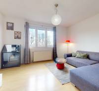 Wohnzimmer in einer 3-Zimmer-Wohnung mit Sofa, Tisch und Boden in Holzoptik.