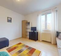 Wohnzimmer in einer 3-Zimmer-Wohnung mit Sofa, Schrank und Boden in Holzoptik.