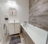 Badezimmer in einer 3-Zimmer-Wohnung mit Badewanne, Waschbecken und Boden in Holzoptik.