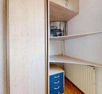 Eckschreibtisch mit Regalen, Kommode und Schrank in einer 3-Zimmer-Wohnung. Boden mit Holzdekor.