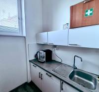 Büroküche mit Schränken, Spüle und Kaffeemaschine.