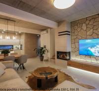 Wohnzimmer in einem Einfamilienhaus mit Kamin, Fernseher an einer Steinwand und Boden mit Holzdekor.