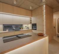 Küche in einem Einfamilienhaus mit eingebauten Geräten, Arbeitsplatten und einem Bodenbelag in Holzoptik.