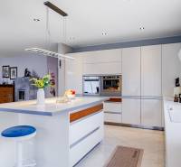 Küche in einem Einfamilienhaus mit Insel, Leuchte, eingebautem Ofen und Zubehör.