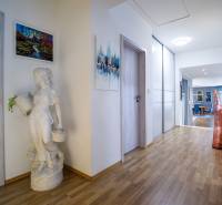 Flur in einem Einfamilienhaus mit Holzboden, dekorative Skulptur und Bilder an den Wänden.