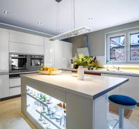 Küche in einem Einfamilienhaus mit zentraler Insel, weißen Schränken und Geräten.